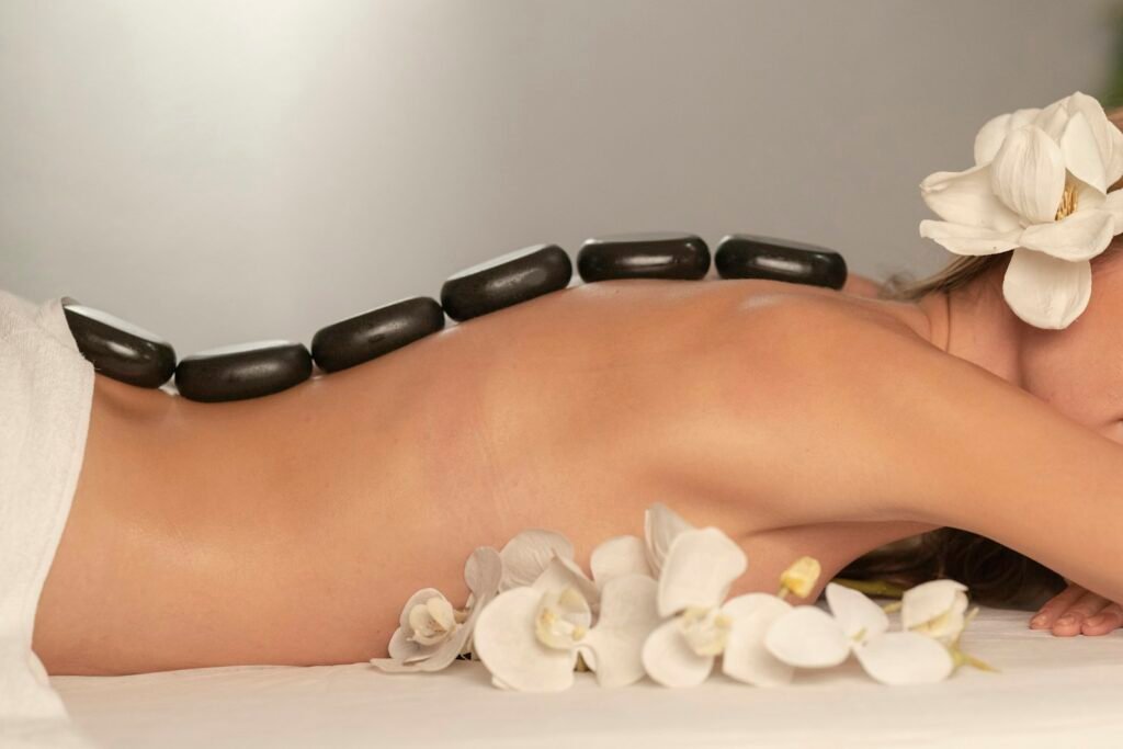 Smooth stones laid along a guest's spine with white orchids