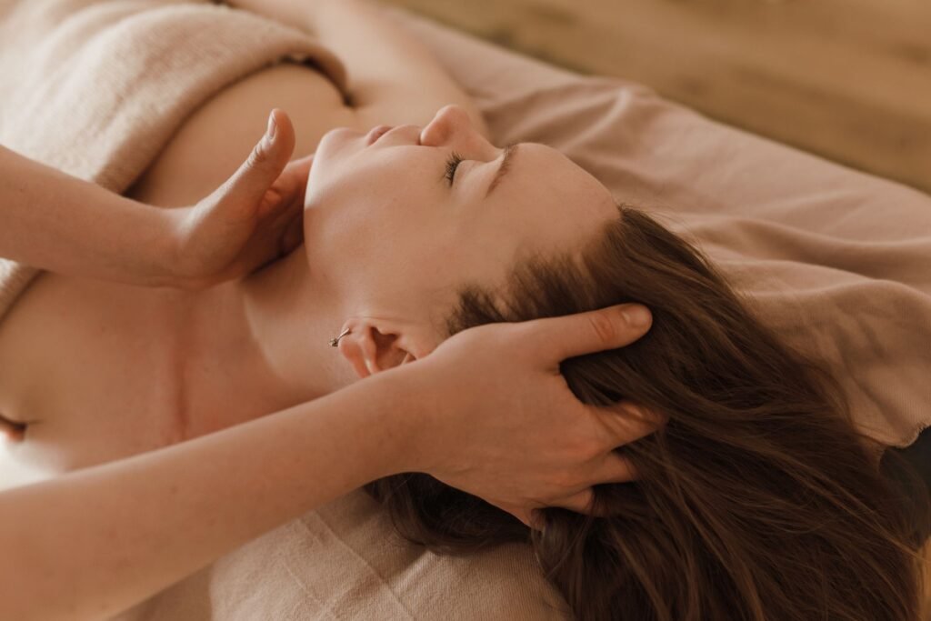 A guest lying back while a therapist massages her head and temples