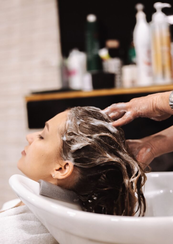 A guest with eyes closed while her scalp is lathered and massaged